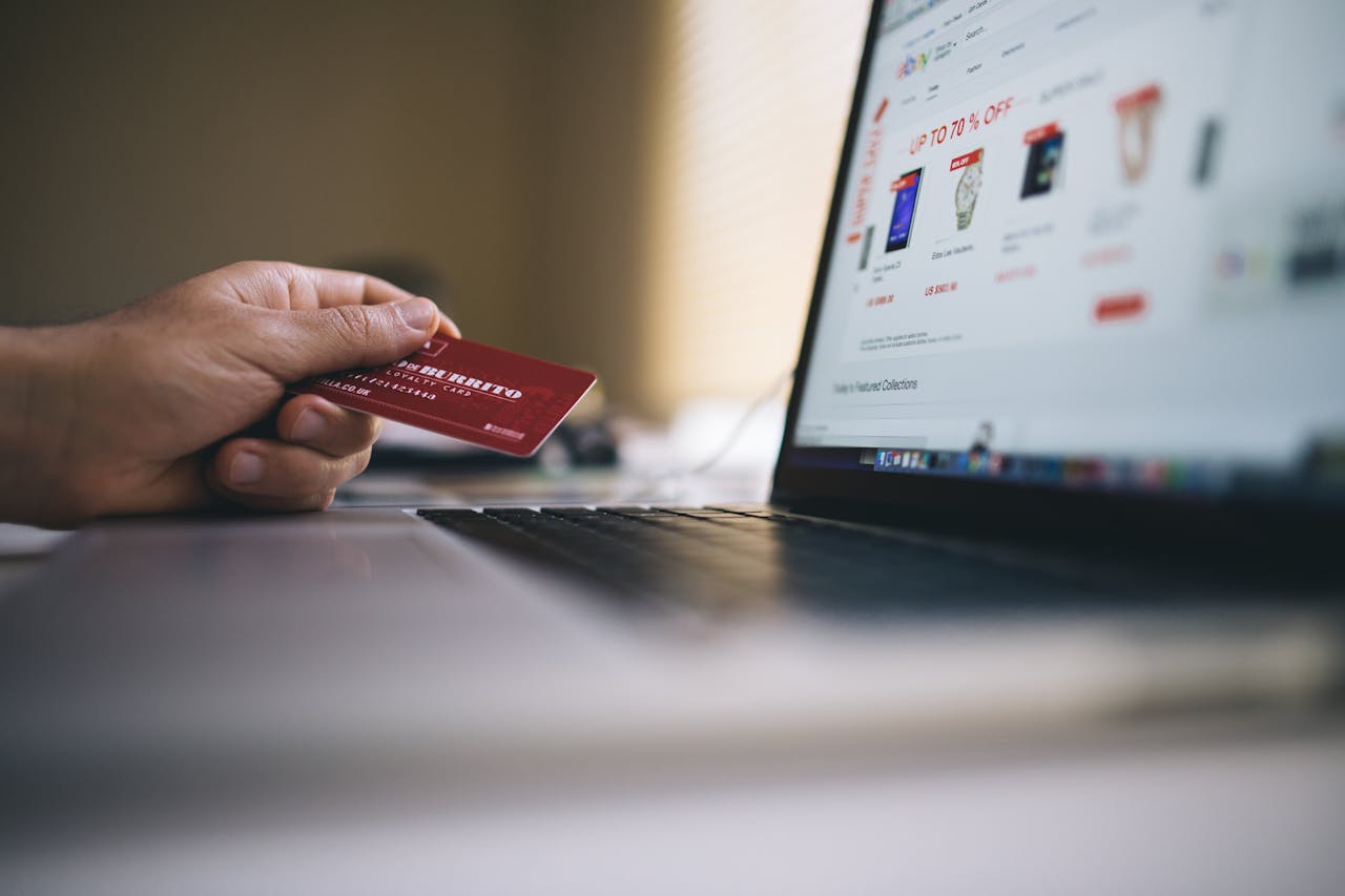 services-02 Person holding a credit card while shopping online on a laptop, indicating ecommerce transactions.