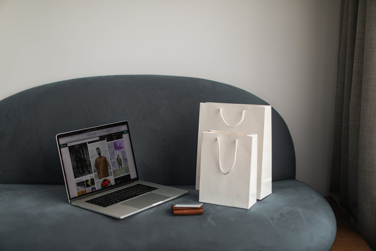 services-03 Online shopping setup with a laptop and shopping bags on a stylish couch.